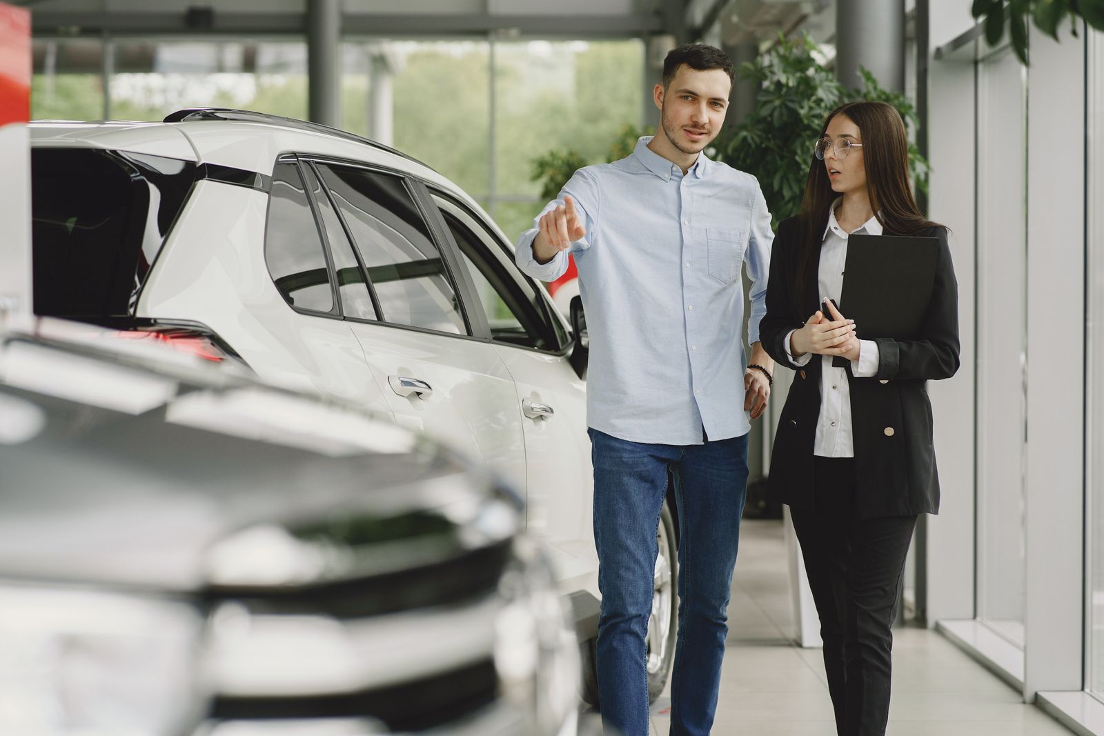 A dealership consultant walking a customer through a car in the showroom